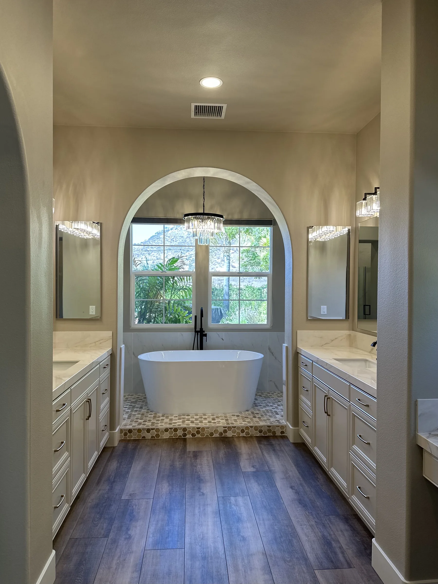 Luxury primary bathroom remodel with arched entry and soaking tub