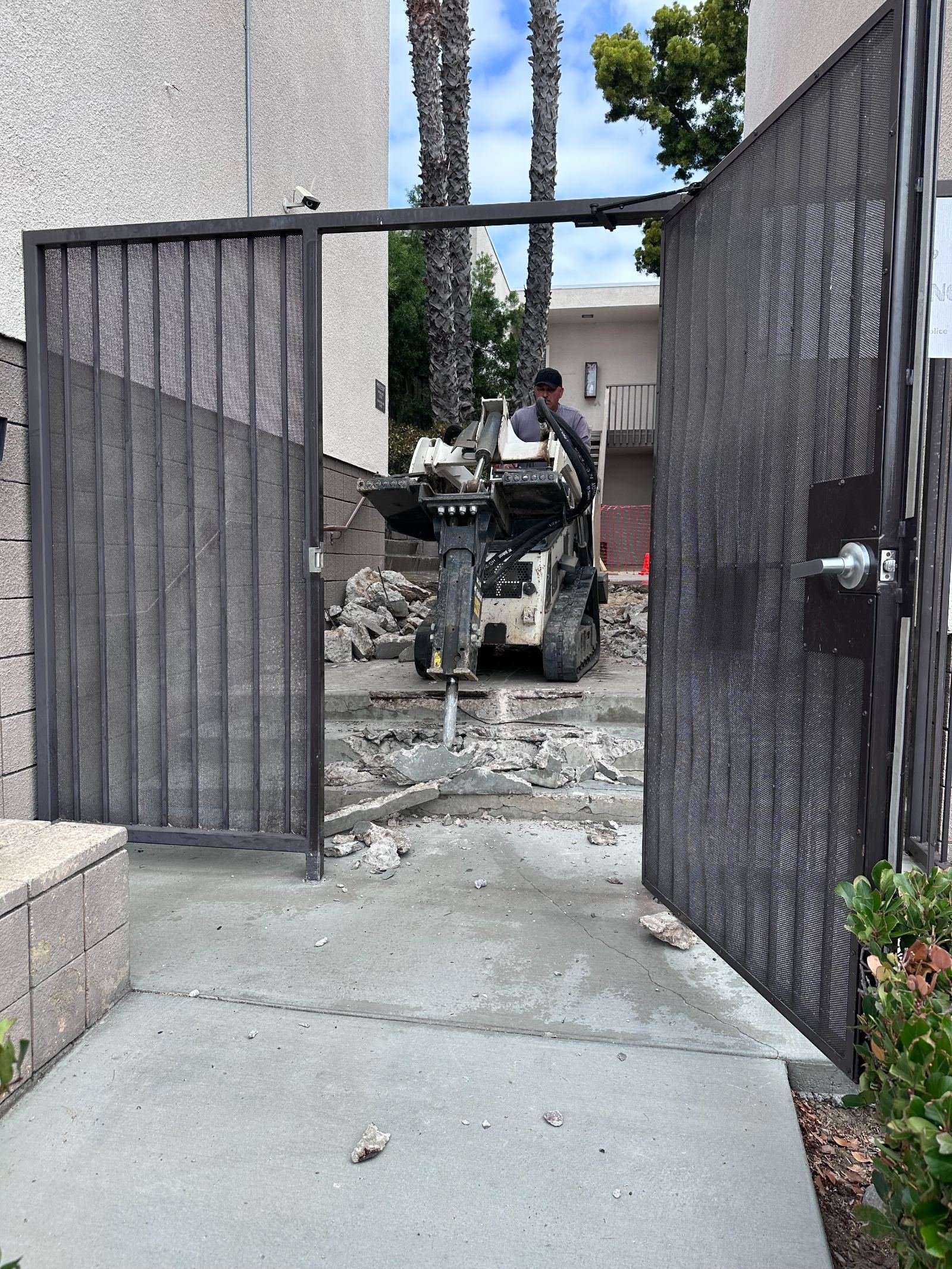 Existing concrete steps and flatwork being broken out with a hydraulic breaker before a new pour