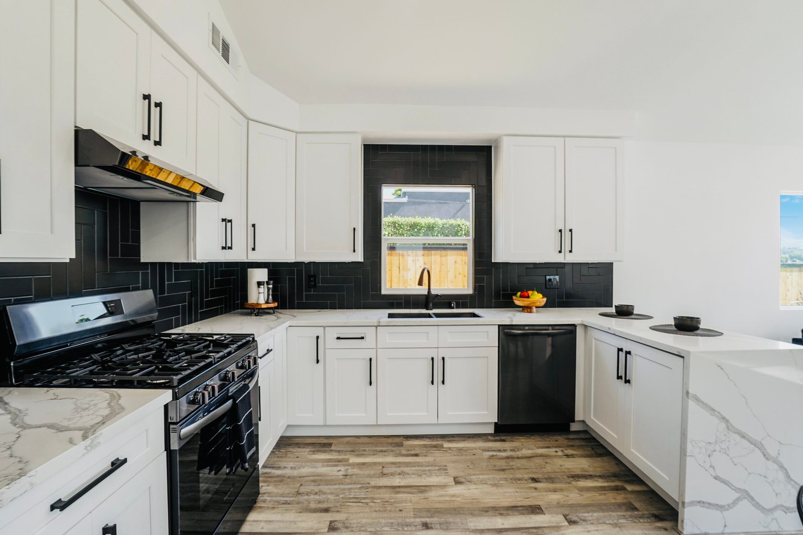 White shaker cabinet kitchen remodel with black subway tile backsplash and marble quartz counters